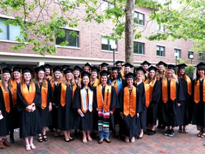 Large group of Western nursing graduates in their black robes, orange hoods, and mortar boards