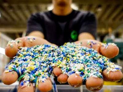 Close up of a man's outstretched hands holding colored plastic granules.